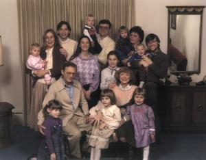 Front row L to R: Nicole Dumes, Shana Simmons, Abby Dumes
2nd row: Stan Dumes and Phyl Dumes.   Behind Stan and Phyl and Sandy Dumes Simmons and Tracey Simmons
Back row: Marsha Bradford holding Hannah Dumes, Harold Dumes, Gary Simmons holding Bill Dumes, Linda Hurley Dumes holding Jeff Dumes, Bruce Dumes holding Greg Dumes
Hannukah 1985 in Stan & Phyl Dumes home in Vincennes (1985)