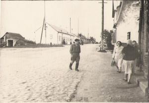 Aglonas Street in Vishki.  Tanya Dumesh has a handbag and is wearing a nurse's uniform.  The hospital, which is the white stone building behind her, was Boris Usdin's house. (~1962)